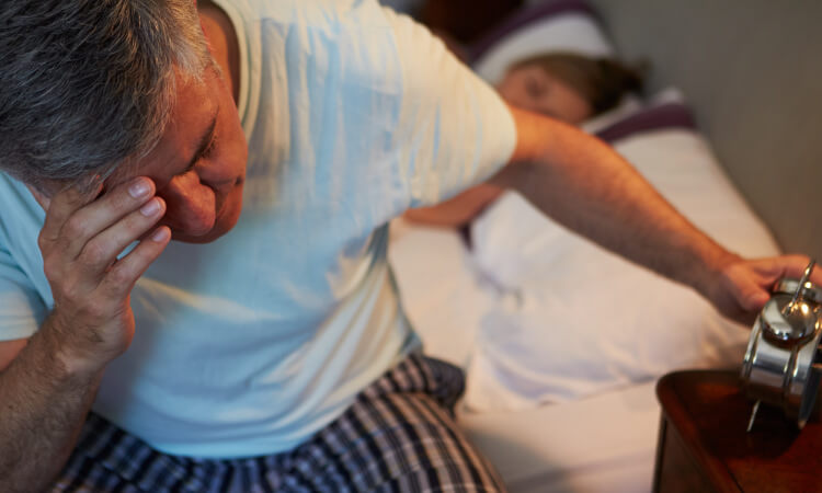 elderly man tired turning off alarm clock